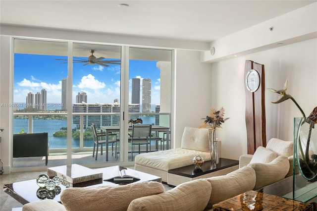 living room with ceiling fan, a water view, and plenty of natural light