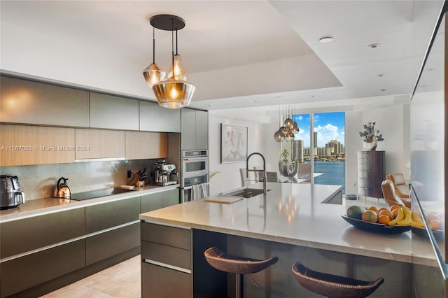 kitchen with hanging light fixtures, backsplash, sink, and light stone counters