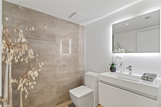 bathroom with tile walls, toilet, and vanity