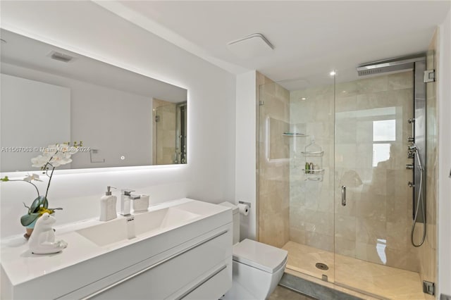 bathroom featuring toilet, vanity, and a shower with shower door