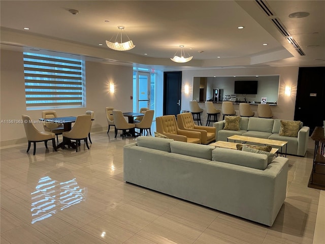 tiled living room with a chandelier and a raised ceiling