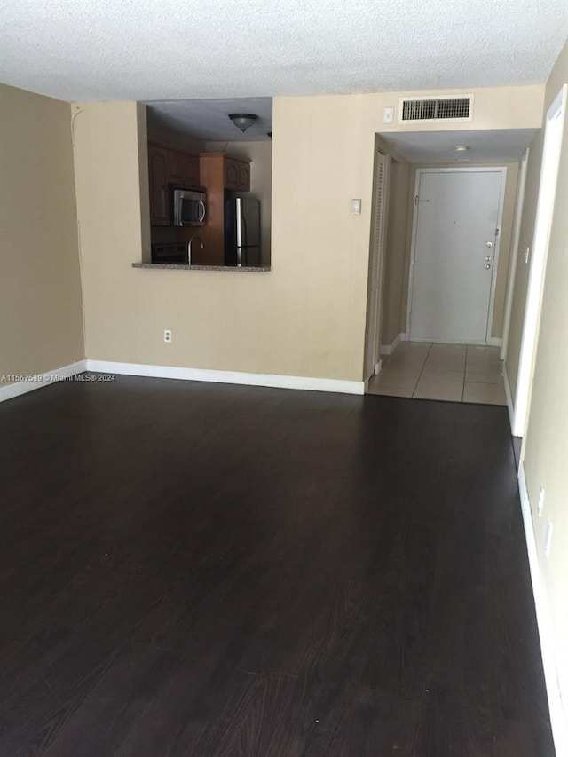 unfurnished room featuring sink, a textured ceiling, and dark tile flooring