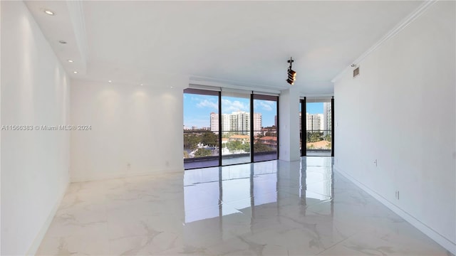 tiled spare room with ornamental molding and expansive windows