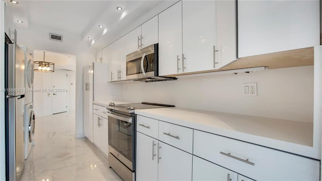 kitchen with appliances with stainless steel finishes, light tile flooring, and white cabinets