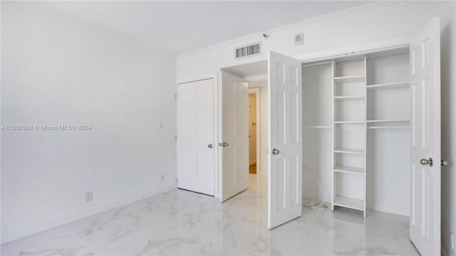 unfurnished bedroom featuring ornamental molding, a closet, and light tile flooring