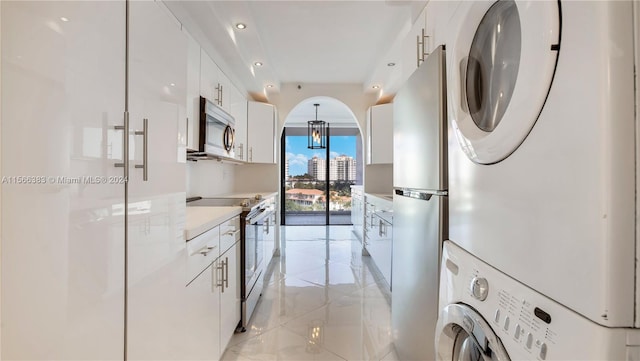 laundry area with stacked washer and dryer and light tile floors