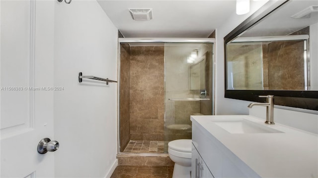 bathroom with a shower with shower door, toilet, tile flooring, and vanity