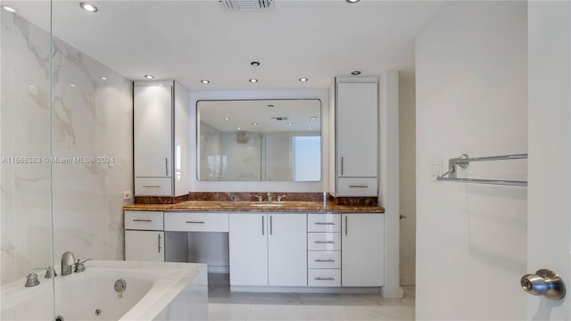 bathroom featuring tile flooring, tiled tub, and vanity