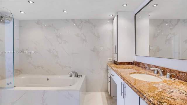 bathroom with vanity with extensive cabinet space, tiled tub, and tile walls