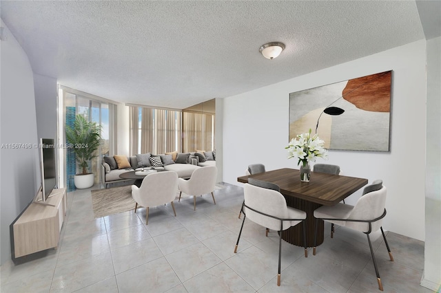 dining space featuring a textured ceiling, a wall of windows, and light tile patterned flooring