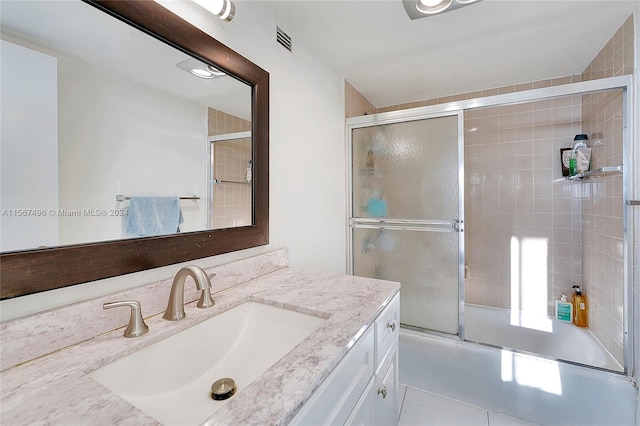 bathroom featuring vanity, tile patterned floors, and enclosed tub / shower combo