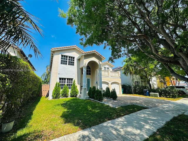 mediterranean / spanish-style home with a garage, a balcony, and a front lawn