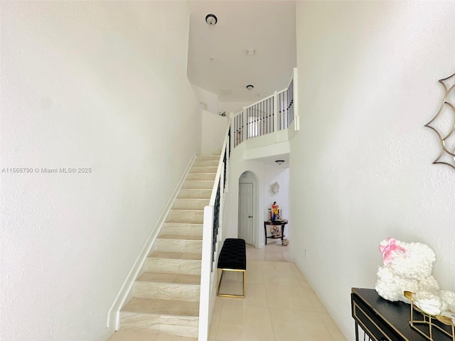 stairway featuring a high ceiling and tile patterned floors