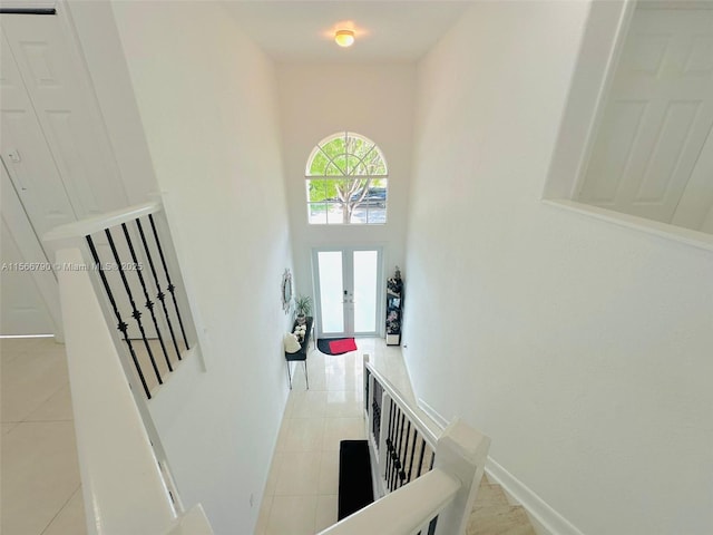 interior space with french doors, a towering ceiling, and light tile patterned flooring