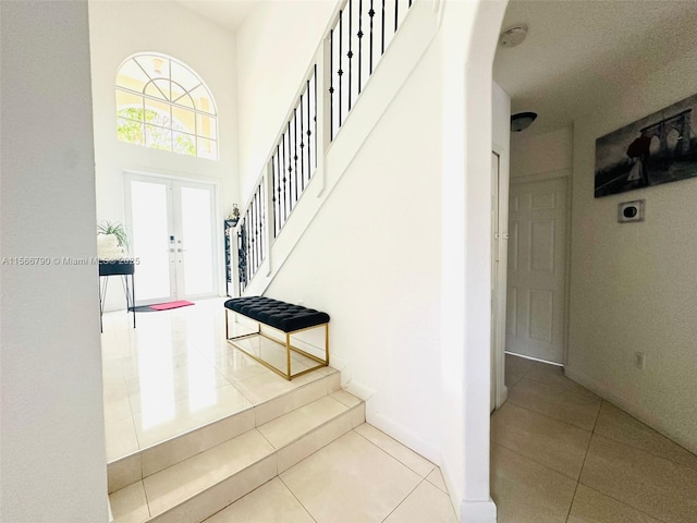 stairway with french doors, a towering ceiling, and tile patterned floors