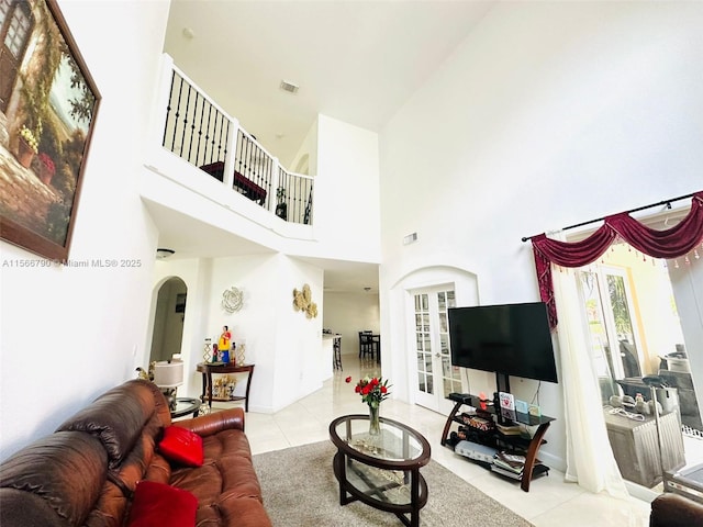 tiled living room featuring french doors and a high ceiling