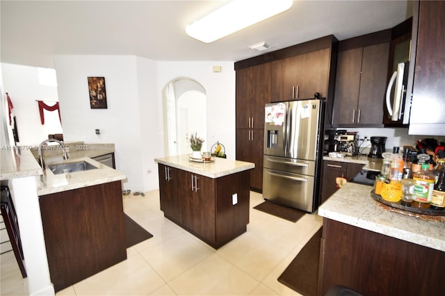 kitchen with sink, stainless steel appliances, light stone countertops, and a kitchen island