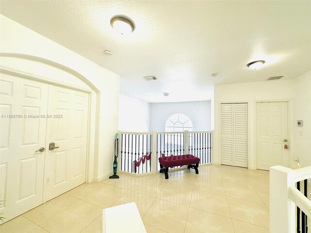 hallway featuring a textured ceiling and light tile patterned floors