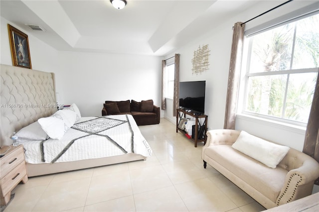 tiled bedroom featuring multiple windows and a tray ceiling