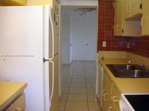 kitchen with tasteful backsplash, ceiling fan, white appliances, light tile floors, and sink