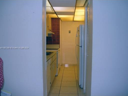 hallway with a paneled ceiling and light tile flooring