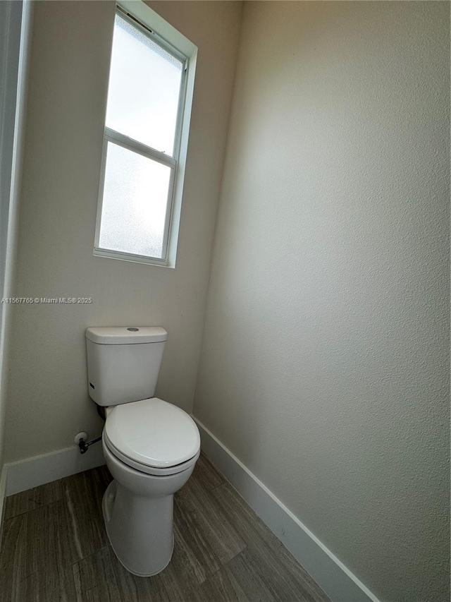 bathroom with plenty of natural light, toilet, and wood-type flooring