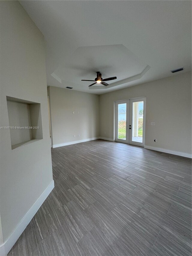 empty room featuring a raised ceiling, ceiling fan, and french doors