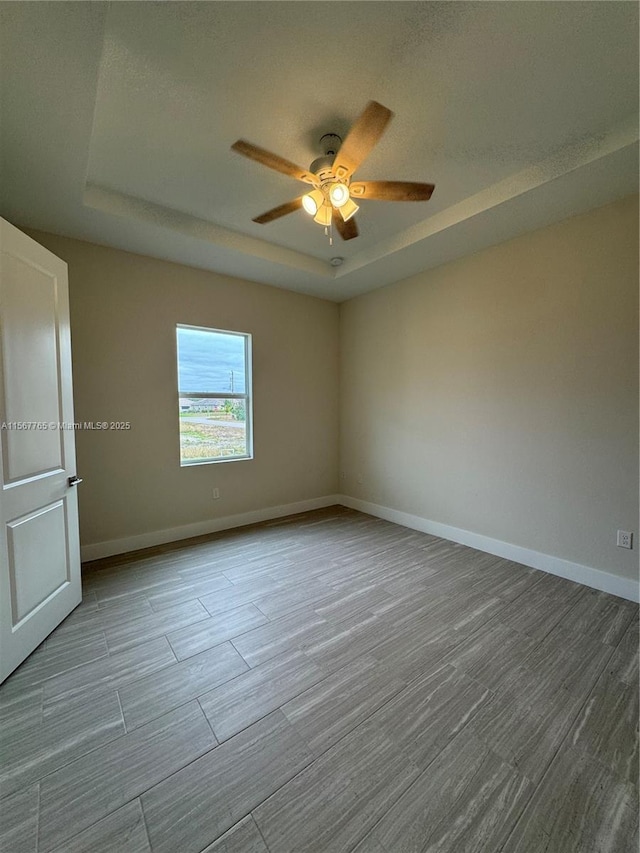 unfurnished room with a raised ceiling and ceiling fan