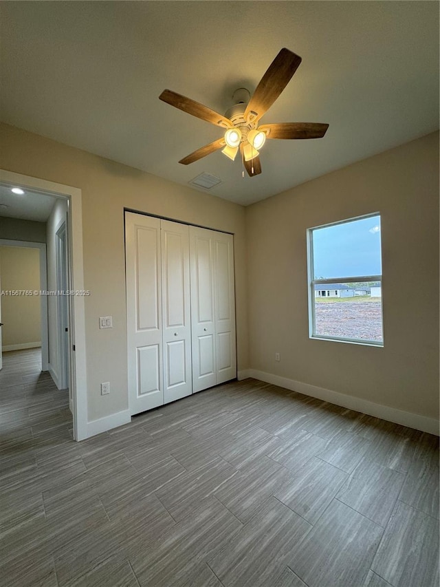 unfurnished bedroom with ceiling fan and a closet