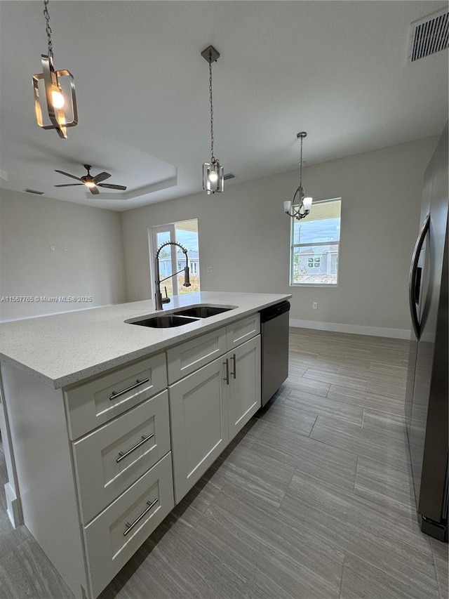 kitchen with black refrigerator, white cabinetry, dishwasher, sink, and a center island with sink