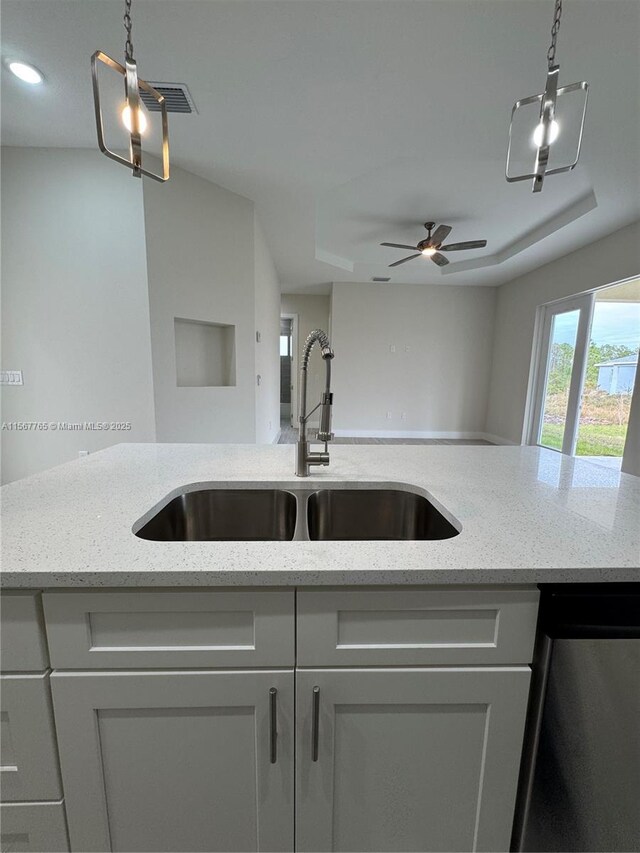 kitchen featuring light stone counters, decorative light fixtures, dishwasher, and sink