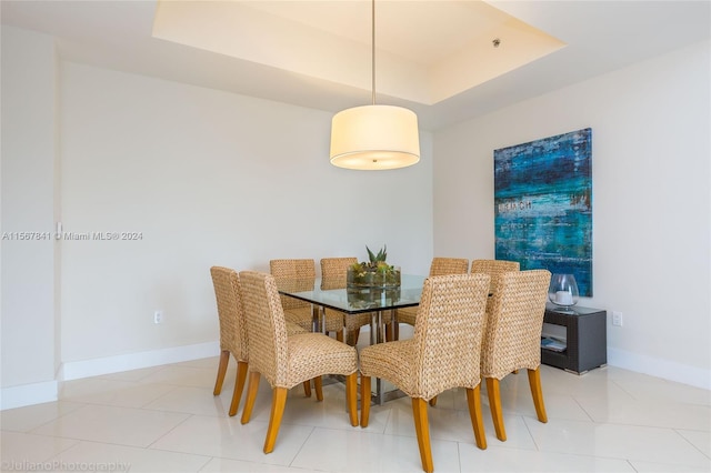 dining space with a raised ceiling and light tile floors