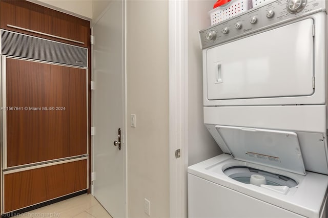 washroom featuring stacked washer / dryer and light tile floors