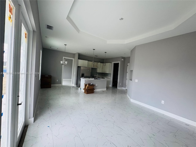 unfurnished living room with a raised ceiling, a wealth of natural light, and sink