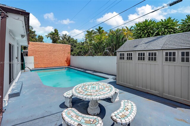 view of pool featuring an outbuilding, a patio, a fenced backyard, and a fenced in pool