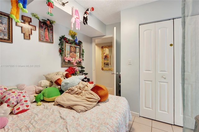 bedroom with a closet, light tile patterned flooring, and a textured ceiling