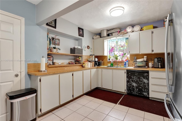 kitchen with black dishwasher, light countertops, backsplash, freestanding refrigerator, and white cabinetry