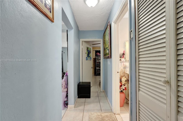 corridor featuring a textured ceiling and light tile patterned floors