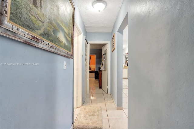 corridor with light tile patterned floors and a textured ceiling