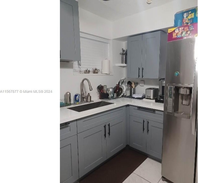 kitchen featuring gray cabinetry, sink, light tile floors, and stainless steel fridge