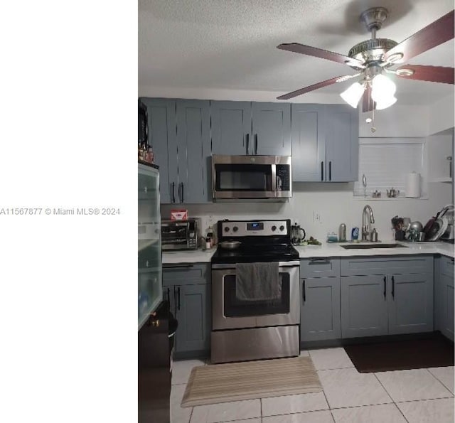 kitchen featuring light tile flooring, gray cabinetry, stainless steel appliances, sink, and ceiling fan