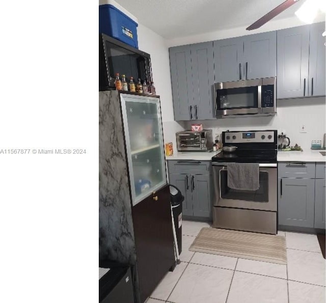 kitchen featuring gray cabinetry, appliances with stainless steel finishes, ceiling fan, and light tile floors