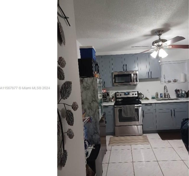 kitchen with appliances with stainless steel finishes, ceiling fan, light tile floors, sink, and gray cabinets