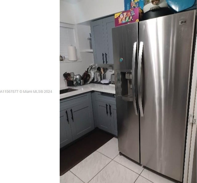 kitchen with gray cabinetry, light tile floors, and stainless steel fridge with ice dispenser