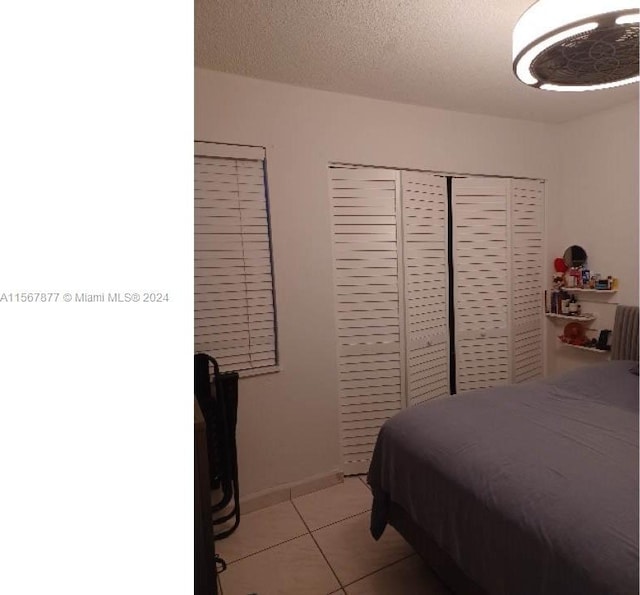 bedroom featuring a closet, light tile floors, and a textured ceiling