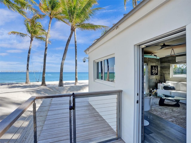 wooden deck featuring ceiling fan, a wall mounted air conditioner, and a water view