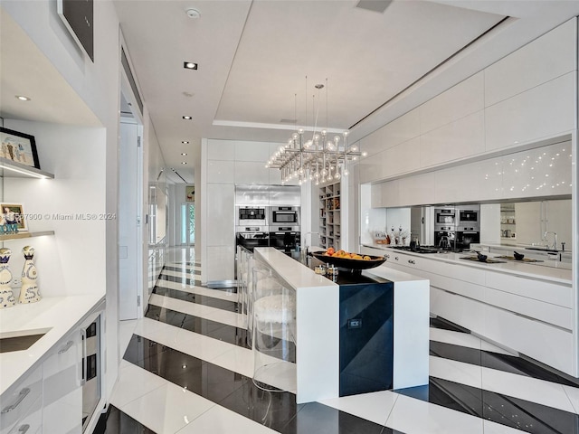 kitchen with a center island, pendant lighting, white cabinets, a notable chandelier, and light tile floors