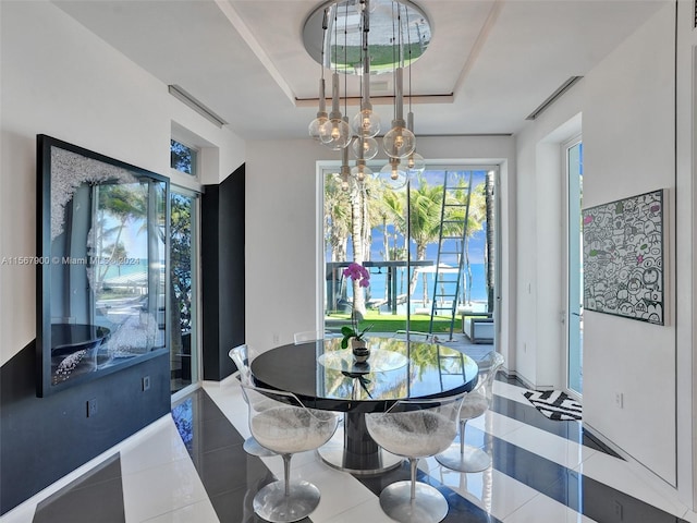 tiled dining area featuring a notable chandelier and a tray ceiling