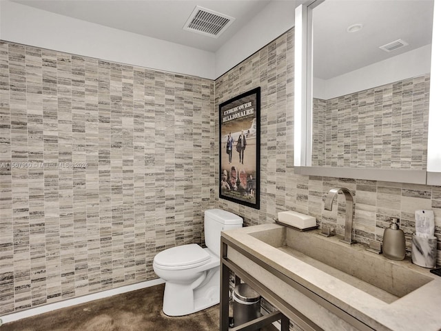 bathroom with vanity, toilet, and tile walls