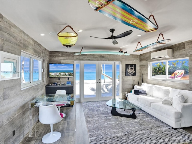 living room featuring french doors, a healthy amount of sunlight, ceiling fan, and a wall unit AC